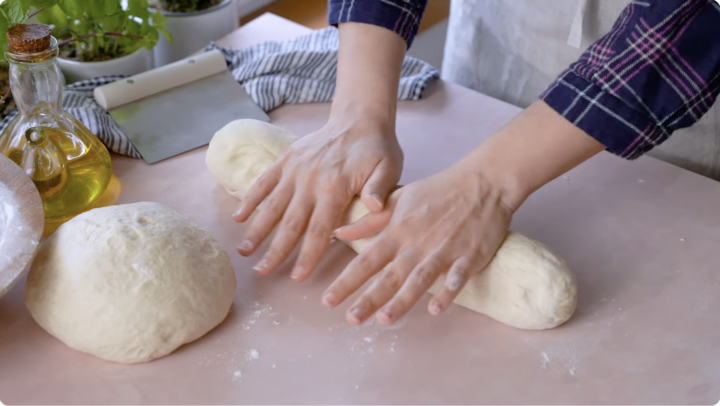 Rolling out Italian bread loaves by hand to make oval loaves