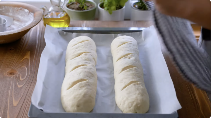 Rising shaped Italian loaves on a baking pan