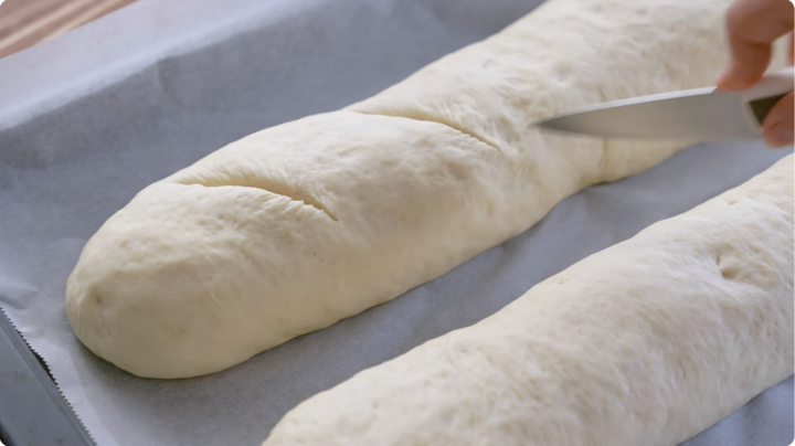 slashing Italian bread loaves with a sharp knife diagonally