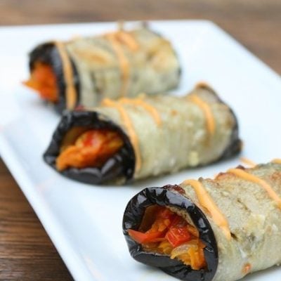Baked eggplant rollups stuffed with vegetables and topped with garlic aioli.