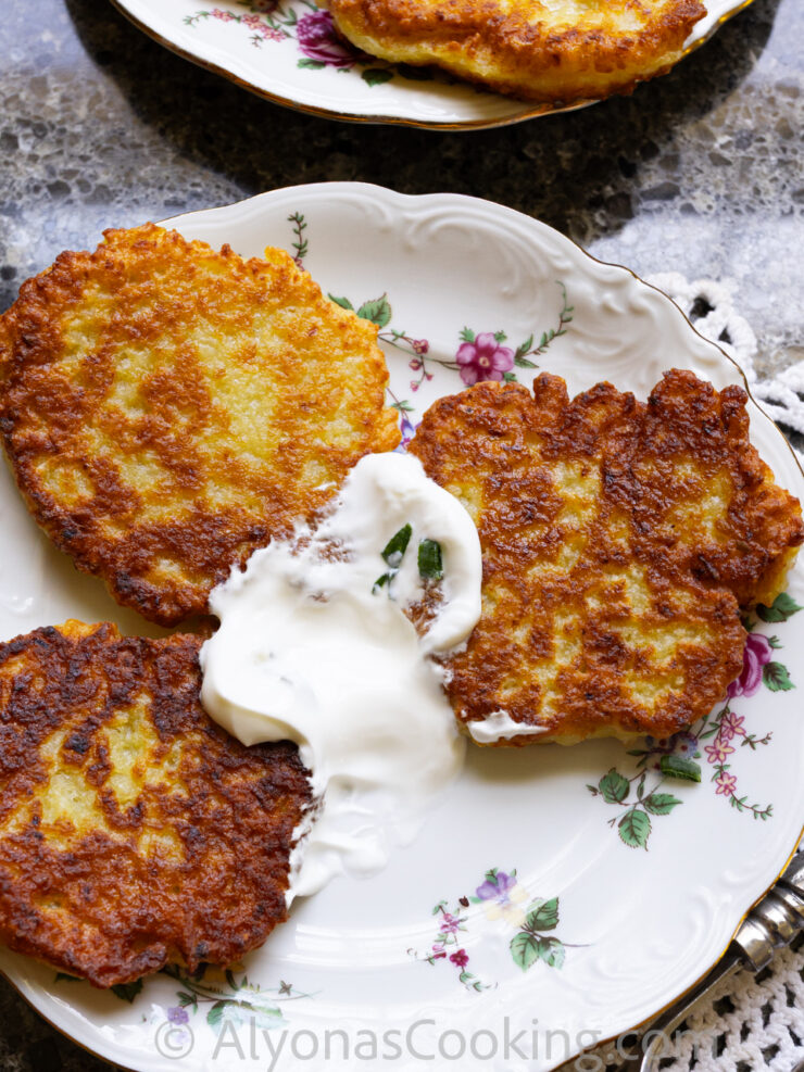 image of three potato pancakes on a plate with sour cream