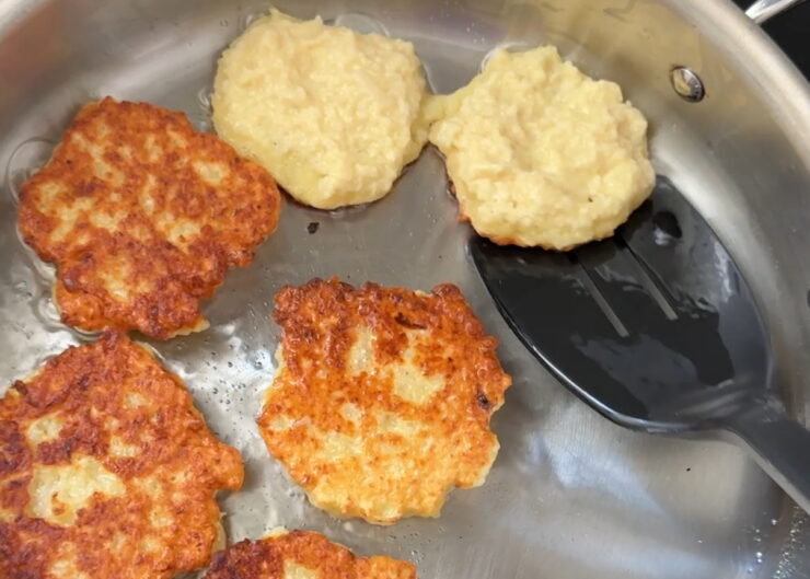 image of crispy potato pancakes being flipped over to the other side in a skillet