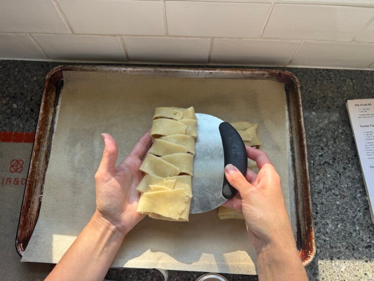 image of Alyona transferring a braided apple hand pie to a baking sheet using a bench scraper
