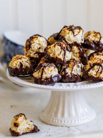 easy homemade coconut macaroons dipped in chocolate on a cake stand drizzled with chocolate