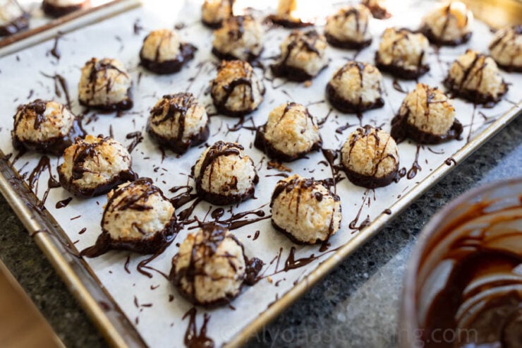 image of coconut macaroon cookies dipped and drizzled with melted chocolate on a cookie sheet