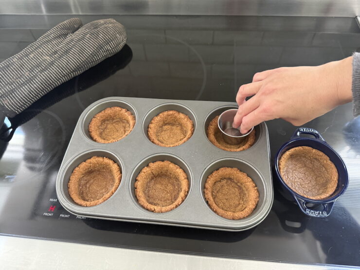 image of tarts being pressed down with a saucer to indent the graham cracker crust