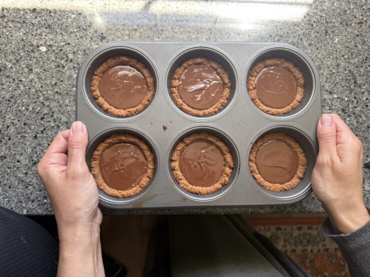 Image of S'more tarts filled with a chocolate ganache and tapped on the counter to flatten