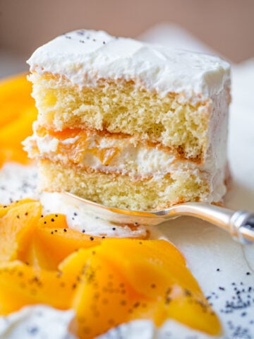 easy peach cake recipe on a serving spoon with peach slices and cream