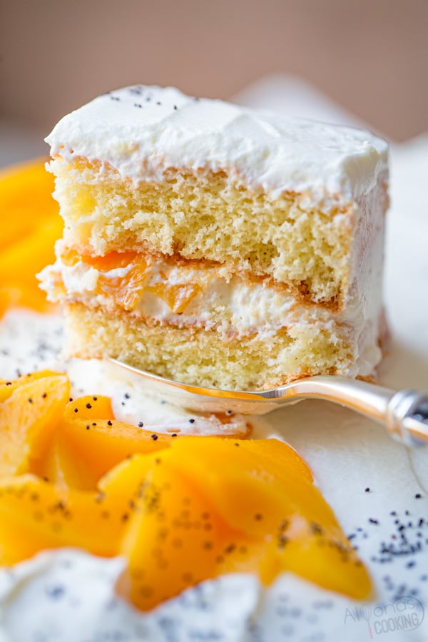 easy peach cake recipe on a serving spoon with peach slices and cream