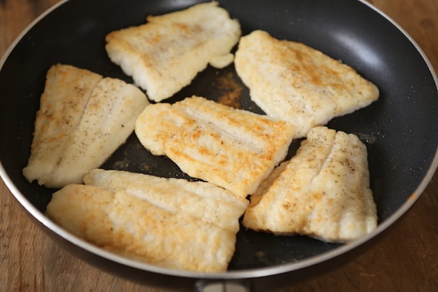 Breaded Swai fillets frying in a pan until golden brown.