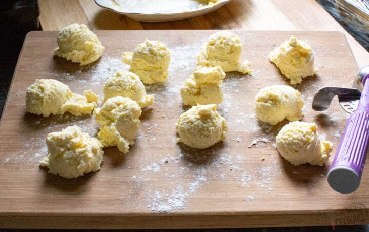 Russian cottage cheese pancakes called Syrniki being shaped on top of a floured cutting board