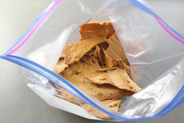 honey cake crumbs being crushed with a rolling pin after they have been dried