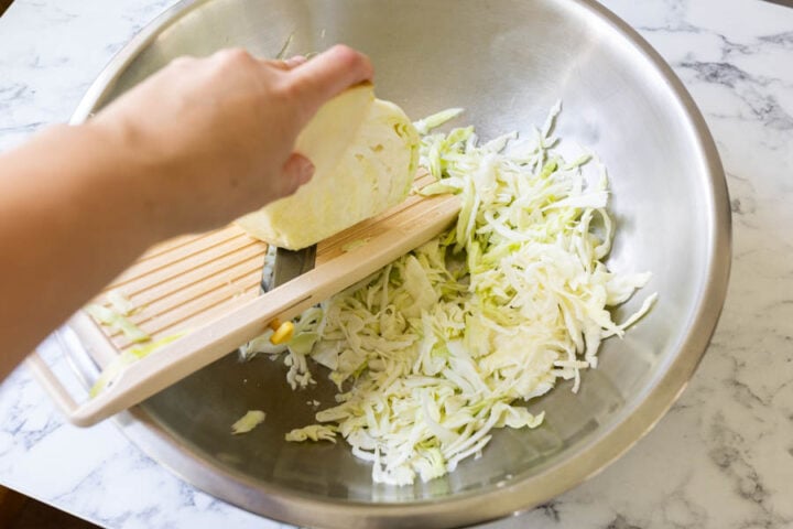 shredding cabbage with a Mandoline for cabbage salad