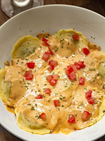 Olive Gardens mushroom ravioli copycat recipe placed on a serving plate garnished with diced tomatoes and dried parsley