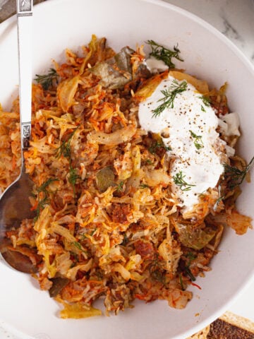 image of unstuffed cabbage rolls on a plate with sour cream and dill