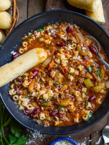 image of homemade pasta e Fagioli soup in a black soup bowl dipped with homemade Olive Garden breadsticks and topped with Parmigiano Reggiano cheese