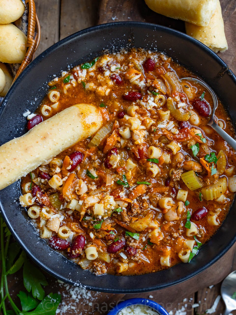 image of homemade pasta e Fagioli soup in a black soup bowl dipped with homemade Olive Garden breadsticks and topped with Parmigiano Reggiano cheese