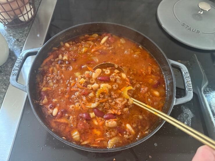 image of homemade pasta e fagioli soup in a Staub pot with a gold-tone soup ladle