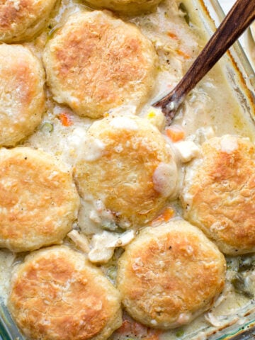 chicken pot pie casserole with biscuits in a glass pyrex baking dish
