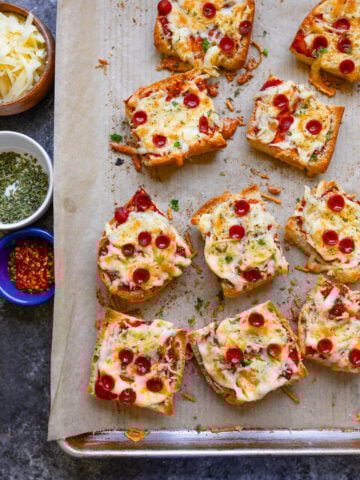 French bread pizza on a baking sheet with pizza toppings