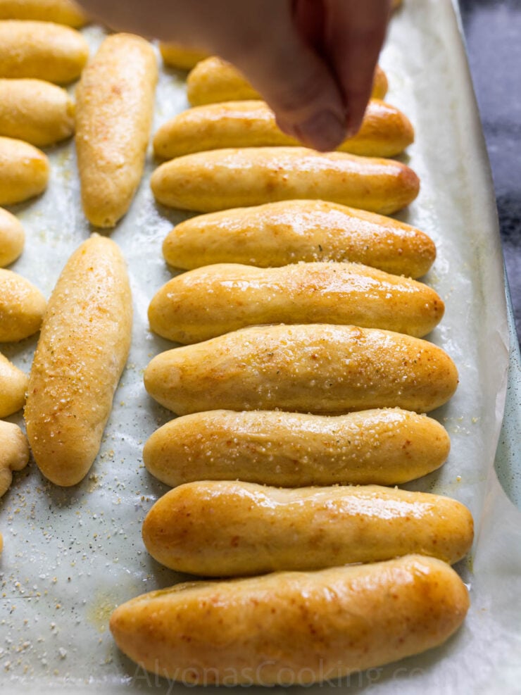 image of Alyona sprinkling garlic salt over buttery homemade breadsticks