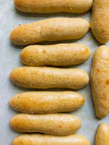 image of buttery, garlicky, and chewy breadsticks like the Olive Garden breadsticks on a pan lined with parchment paper