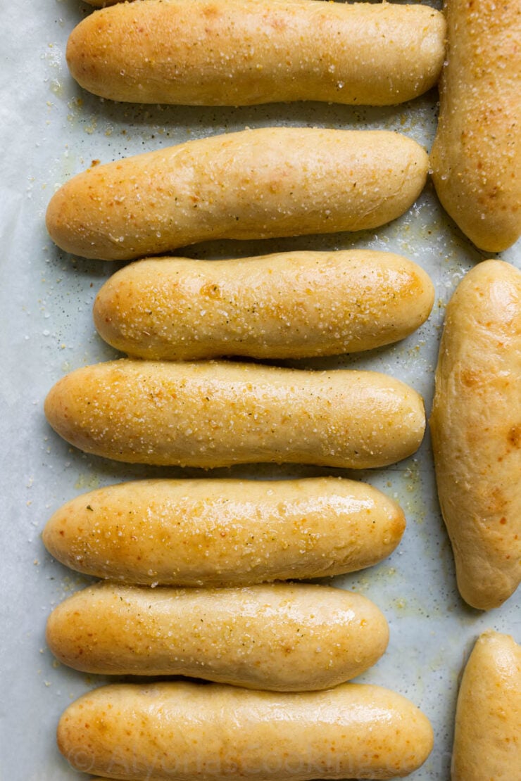 image of buttery, garlicky, and chewy breadsticks like the Olive Garden breadsticks on a pan lined with parchment paper