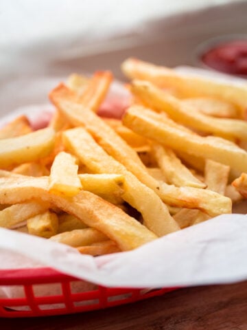 french fries in red woven basket with ketchup