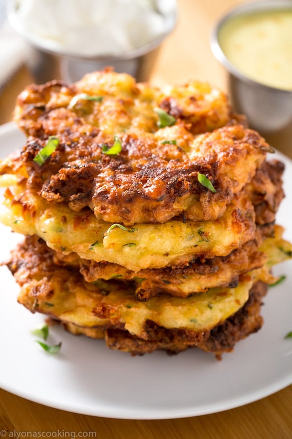 Stack of freshly fried zucchini fritters with a dollop of sour cream