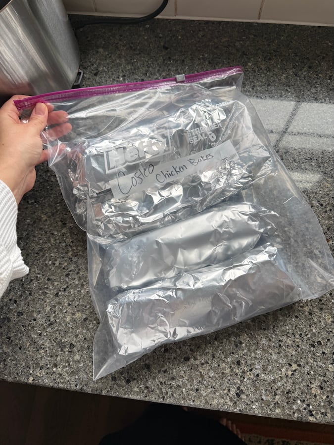image of homemade, foil-wrapped Costco chicken bakes inside a jumbo bag being held by a chef (Alyona)