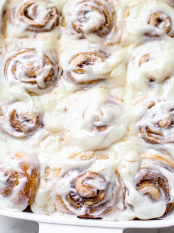 cinnamon rolls like cinnabons copycat in a white baking dish with a cream cheese frosting