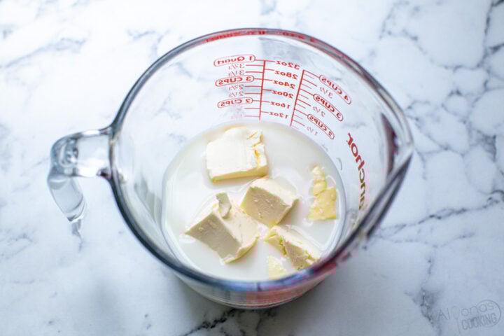 milk and butter in a measuring cup for microwaving the milk for cinnamon rolls