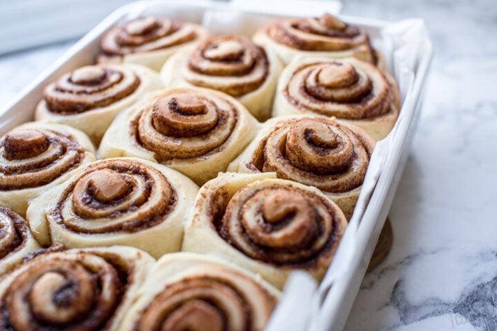 cinnamon rolls in a baking dish with a cinnamon sugar swirl before icing