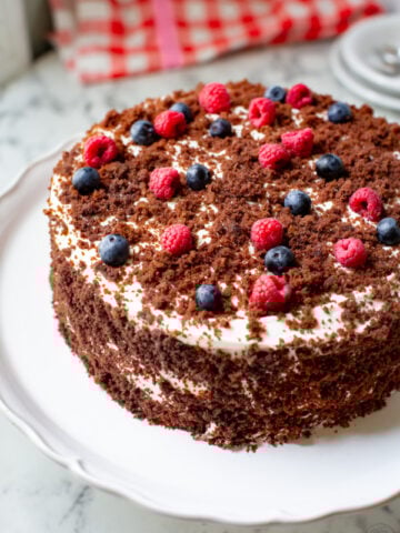a chocolate cake with a cream cheese frosting made from a German chocolate cake mix, fresh blueberries, raspberries and cake crumbs