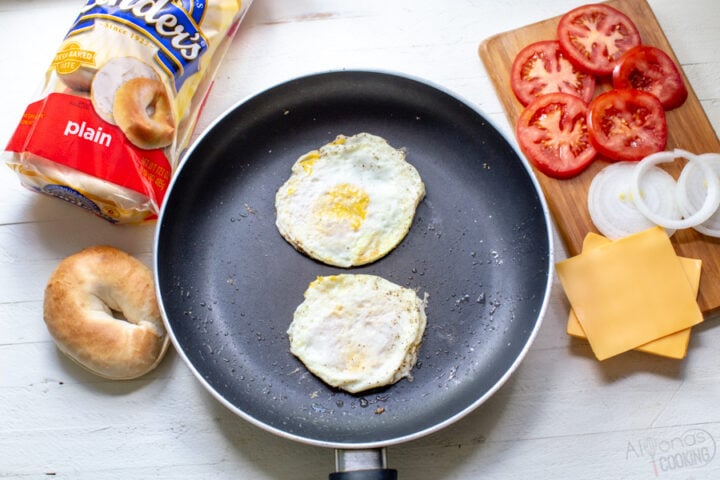 eggs in a skillet seasoned with black pepper and salt for bagel breakfast sandwiches