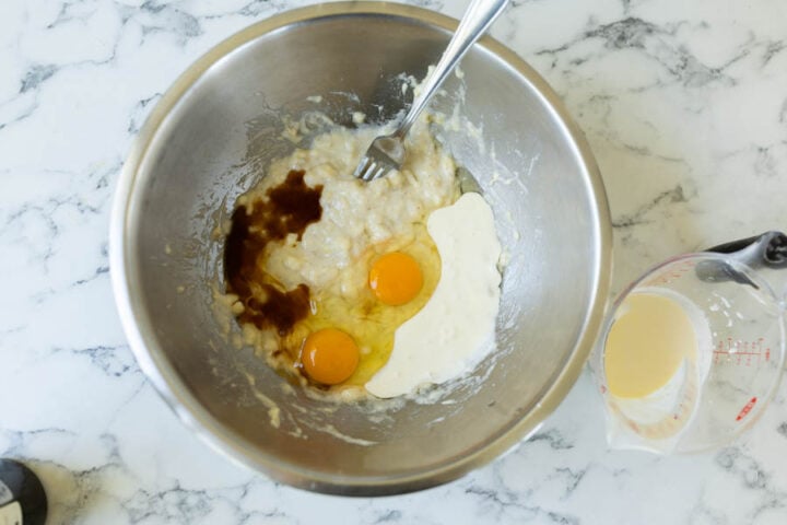 combining the west ingredients for banana bread (mashed bananas, eggs, buttermilk, oil, and vanilla extract)