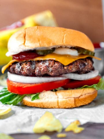 the perfect homemade juicy burger on hamburger buns with lettuce, tomatoes, onion, American cheese, mayo, ketchup, and pickles