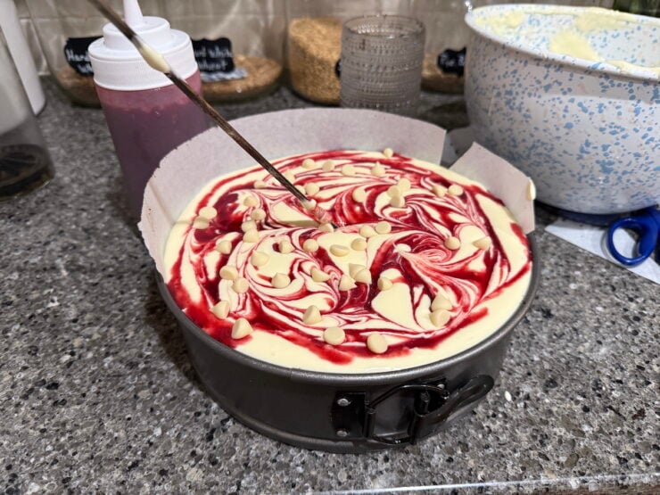 image of a white chocolate raspberry cheesecake swirled with raspberry sauce and white chocolate