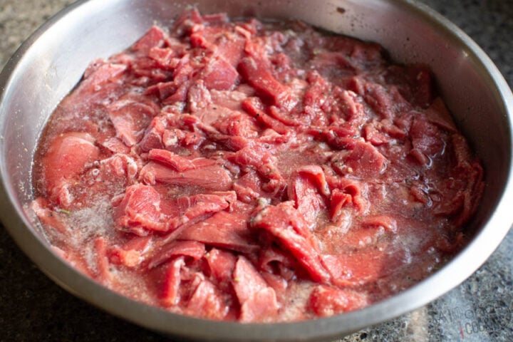 image of marinated beef shavings in seasoning and a quick meat tenderizer for Philly Cheesesteak sandwiches