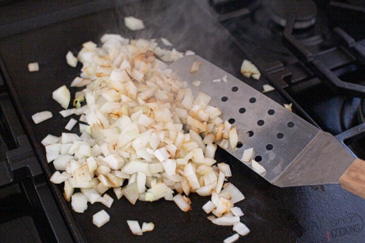 Image of how to cook and sauté onions for a Philly CheeseSteak using a large flat grill spatula