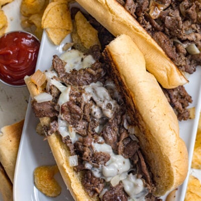 image of Philly cheesesteaks on a plate made from sliced beef, provolone cheese, and fried onions