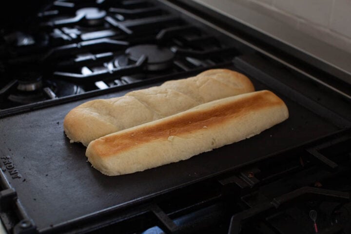 image of submarine bread (hero rolls) being toasted face down on a hot griddle for Philly CheeseSteaks