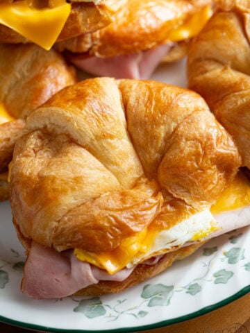 breakfast sandwich made from croissants, eggs, bacon, ham, and American cheese