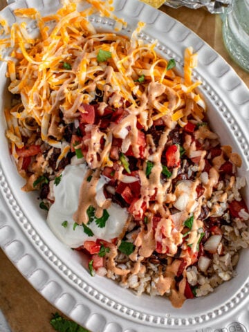 a layered burrito bowl inside an oval plate