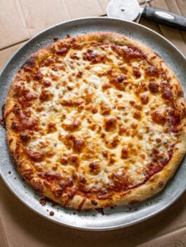 dominos pizza on a pizza pan with holes