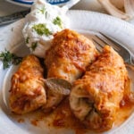 moms stuffed cabbage rolls on a plate filled and rolled with rice and meat then garnished with sour cream and dill