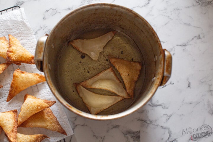 crab rangoons deep-fried in oil and placed on paper towels image