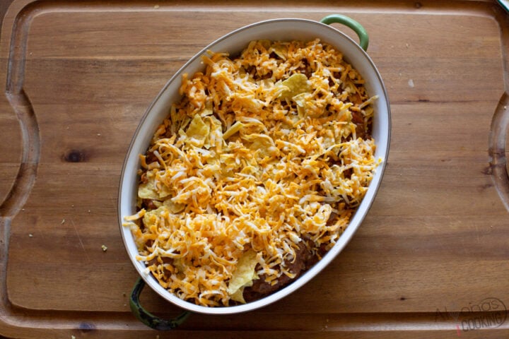 taco casserole recipe made in a 2-quart baking dish and layered with tortilla chips, beans, beef, and cheese. Top with taco topping like lettuce, tomatoes, and onion.
