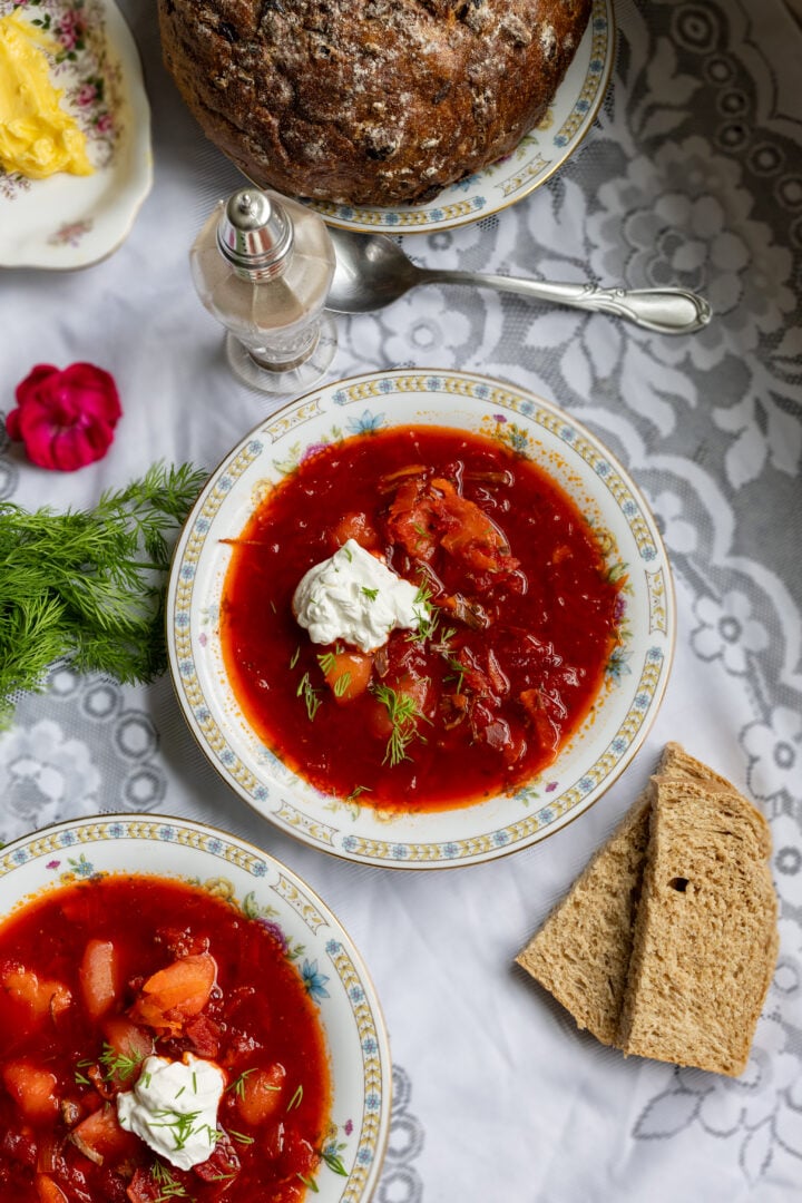 image of traditional Ukrainian red borscht served with whole wheat bread and sour cream