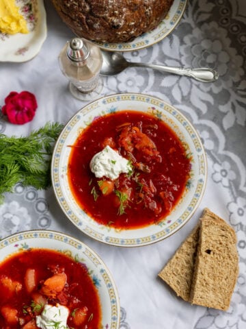image of traditional Ukrainian red borscht served with whole wheat bread and sour cream